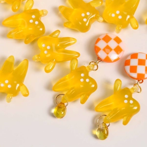 Translucent yellow resin tooth earring with white polka dots and amber teardrop charm