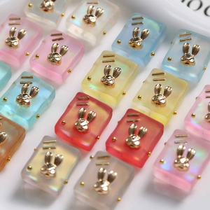 Macro shot of colorful resin square charms with golden bunny inlay for DIY jewelry crafting