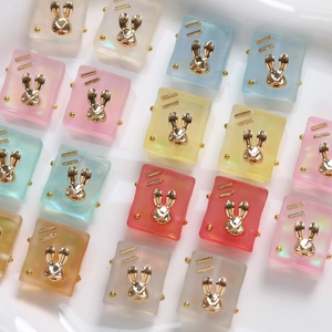 Detailed macro view of colorful frosted resin square charms with golden rabbit inserts