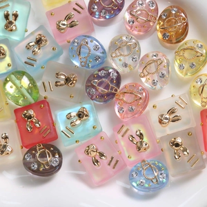 Macro shot of colorful frosted resin charms with gold rabbit and planet inlays for DIY
