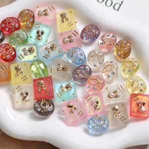 Detailed macro of gradient resin rabbit charms and saturn beads in a white dish