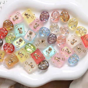 Close-up of frosted resin charms with gold rabbit and planet designs for DIY jewelry