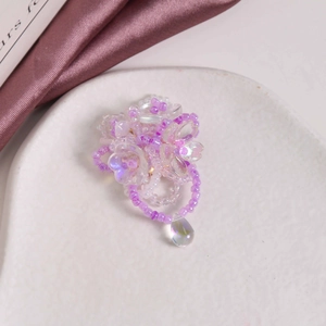 Detail of purple beaded flower jewelry with a colorful iridescent crystal teardrop pendant
