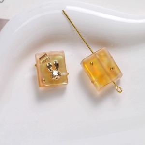 Macro shot of frosted amber resin square beads with golden rabbit head detail for DIY