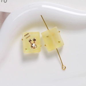 Close-up of frosted square resin beads with gold rabbit charms for DIY jewelry making