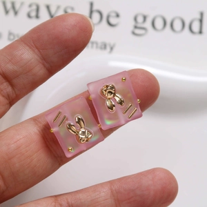 Detailed view of pink frosted resin square charms with gold rabbit inlay for DIY jewelry