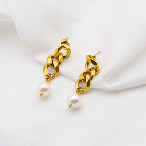 Détail de boucles d'oreilles chaîne cubaine dorée avec perles sur tissu en soie