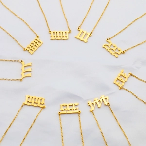 Detailed close-up of gold angel number necklaces arranged on white satin background