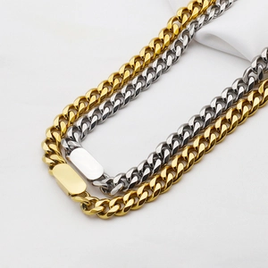 Detail of gold and silver cuban link chains with rectangle clasp on white fabric