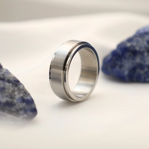 Dettaglio macro di anello rotante in titanio argento con finitura spazzolata e scanalatura