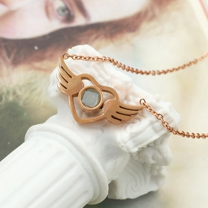 Rose gold angel wings heart pendant necklace with projection stone on white pedestal
