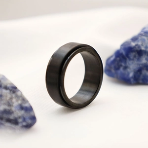 Macro di anello rotante nero in titanio su tessuto bianco con pietre minerali blu