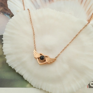 Macro view of rose gold angel wing heart pendant necklace with center projection stone