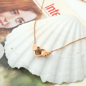 Detail of rose gold angel wing heart pendant with projection stone on white seashell