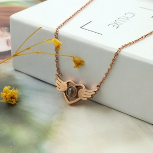 Detail of rose gold heart pendant with angel wings and 100 languages projection stone