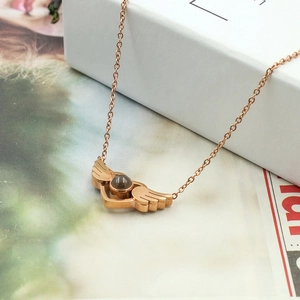 Close-up of rose gold angel wing necklace with round stone on soft background
