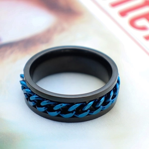 Primer plano de anillo de acero negro mate con cadena azul giratoria y estilo industrial