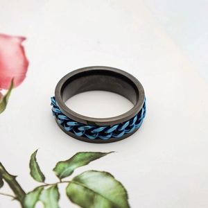 Detalle del anillo para hombre negro mate con cadena azul giratoria sobre la superficie