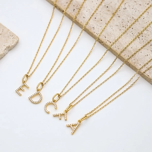 Detailed view of gold-plated necklaces featuring initial pendants set with sparkling zircons