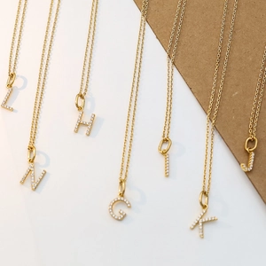 Detailed close-up of gold-plated initial pendants with sparkling micro-pave crystals on chains