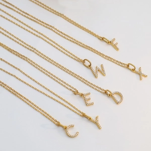 Detailed view of various gold-plated crystal-encrusted letter pendant necklaces