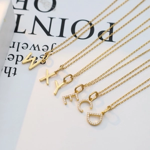 Macro shot of gold letter pendants with polished and crystal pavé finishes on fine chains