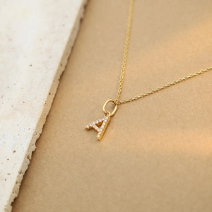 Macro shot of gold-plated A-letter pendant necklace with sparkling pavé zircons