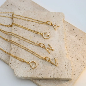 Detailed view of gold plated necklaces with A, G, N, V, D crystal letter pendants