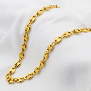 Collier à maillons grain de café doré poli posé sur un tissu de soie blanc élégant