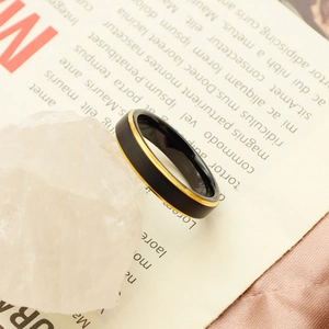 Detail of matte black tungsten ring with thin gold edge on aesthetic magazine background
