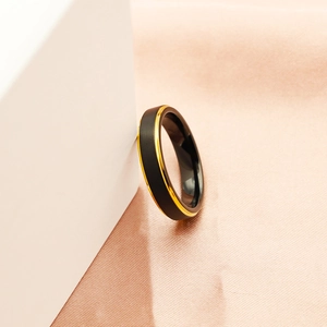 Detailed view of matte black tungsten ring with gold polished inner band on geometric display