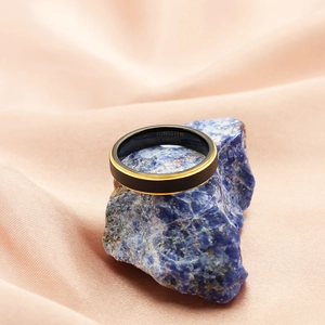 Detail of matte black tungsten carbide ring with gold line on blue stone background