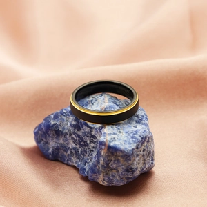 Detail of matte black tungsten carbide ring with gold accent on blue rock