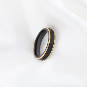 Minimalist matte black tungsten steel ring with a thin gold line on white silk