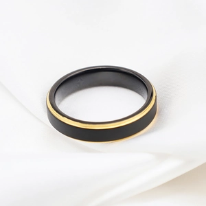 Minimalist black and gold tungsten steel ring displayed on white silk background
