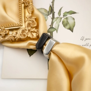 Detail of minimalist geometric rings in black and silver finishes on elegant champagne silk