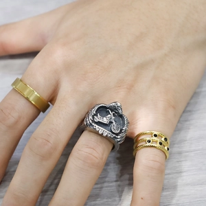 Detail of vintage silver motorcycle embossed ring styled with minimalist gold bands