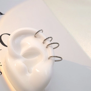 Lot de quatre anneaux de cartilage en titane argenté présentés sur un modèle d'oreille