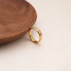 Bague en titane doré poli sertie d'un zircon cubique sur un plateau en bois naturel