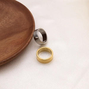 Minimalist 18K gold and silver titanium steel rings set on pink silk fabric background