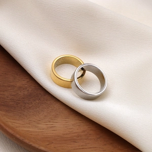 Minimalist irregular titanium steel rings in gold and silver colors on wooden tray