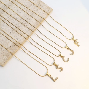 Detailansicht goldener Schlangenketten mit eleganten, perlenbesetzten Anfangsbuchstaben