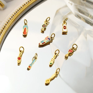 Detailed view of nine colorful enamel jewelry charms on a mirrored tray with gold plating