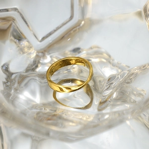 Vue macro d'une bague Mobius dorée au fini poli présentée dans un récipient en cristal