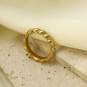 Detailopname van de vergulde gedraaide ring op een elegante stenen en stoffen achtergrond