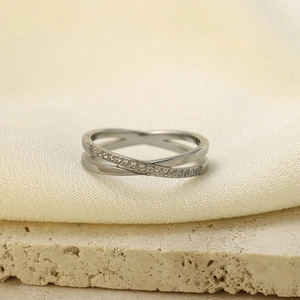 Macro shot of silver crisscross ring featuring micro-pave cubic zirconia on textured fabric