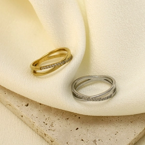 Crossed rhinestone rings in gold and silver finish on elegant textured background