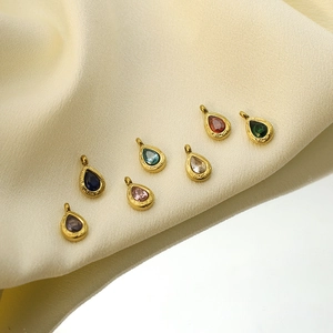 Detail of teardrop birthstone pendants in gold plated setting on a soft fabric background