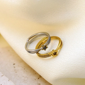 Star-shaped rhinestone titanium steel rings in gold and silver colors on silk background