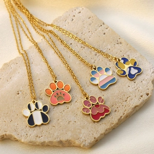 Close-up of five colorful cat paw pendants with gold plating on textured stone